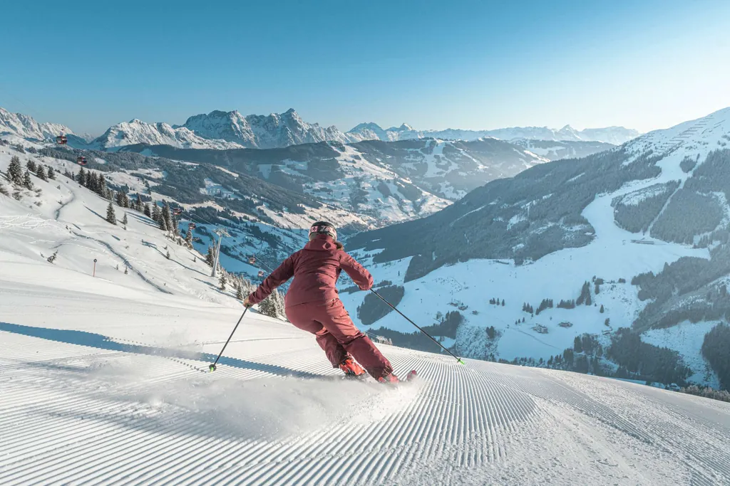 Skifahrerin bei der Abfahrt im Skicircus Saalbach-Hinterglemm, im Hintergrund Blick ins Tal