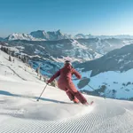 Skifahrerin bei der Abfahrt im Skicircus Saalbach-Hinterglemm, im Hintergrund Blick ins Tal