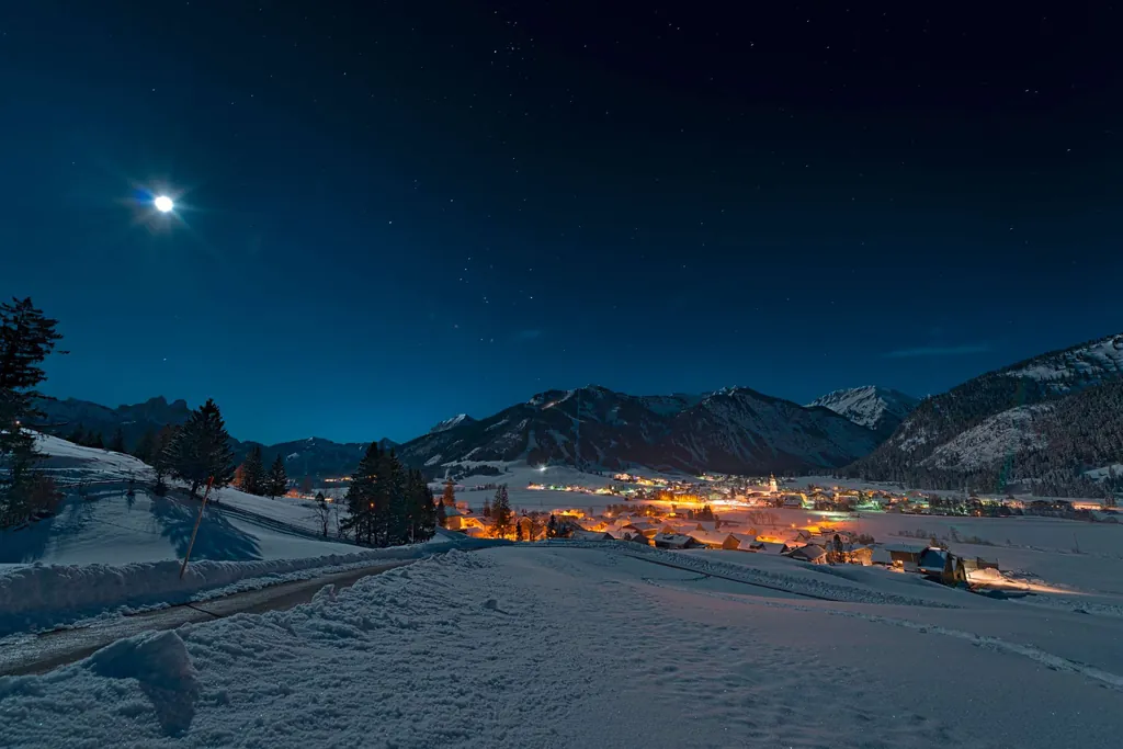 Blick auf das beleuchtete Tannheim im Winter bei Nacht