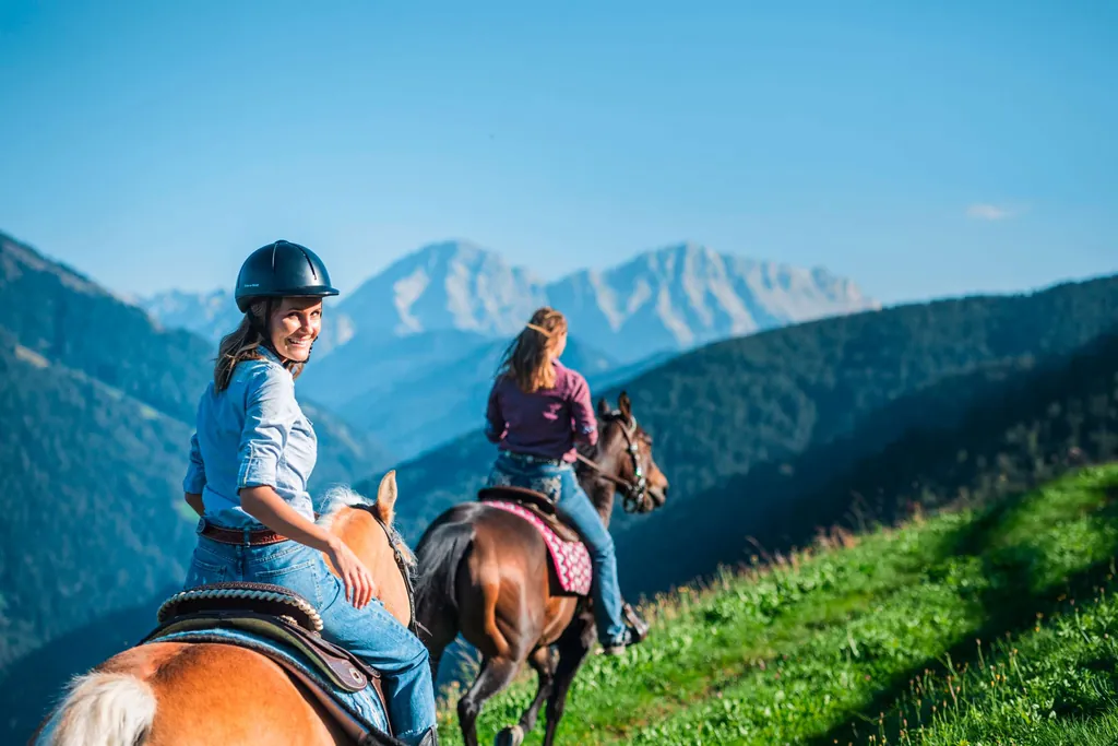 Zwei Frauen auf Pferden beim Reiten in den Bergen
