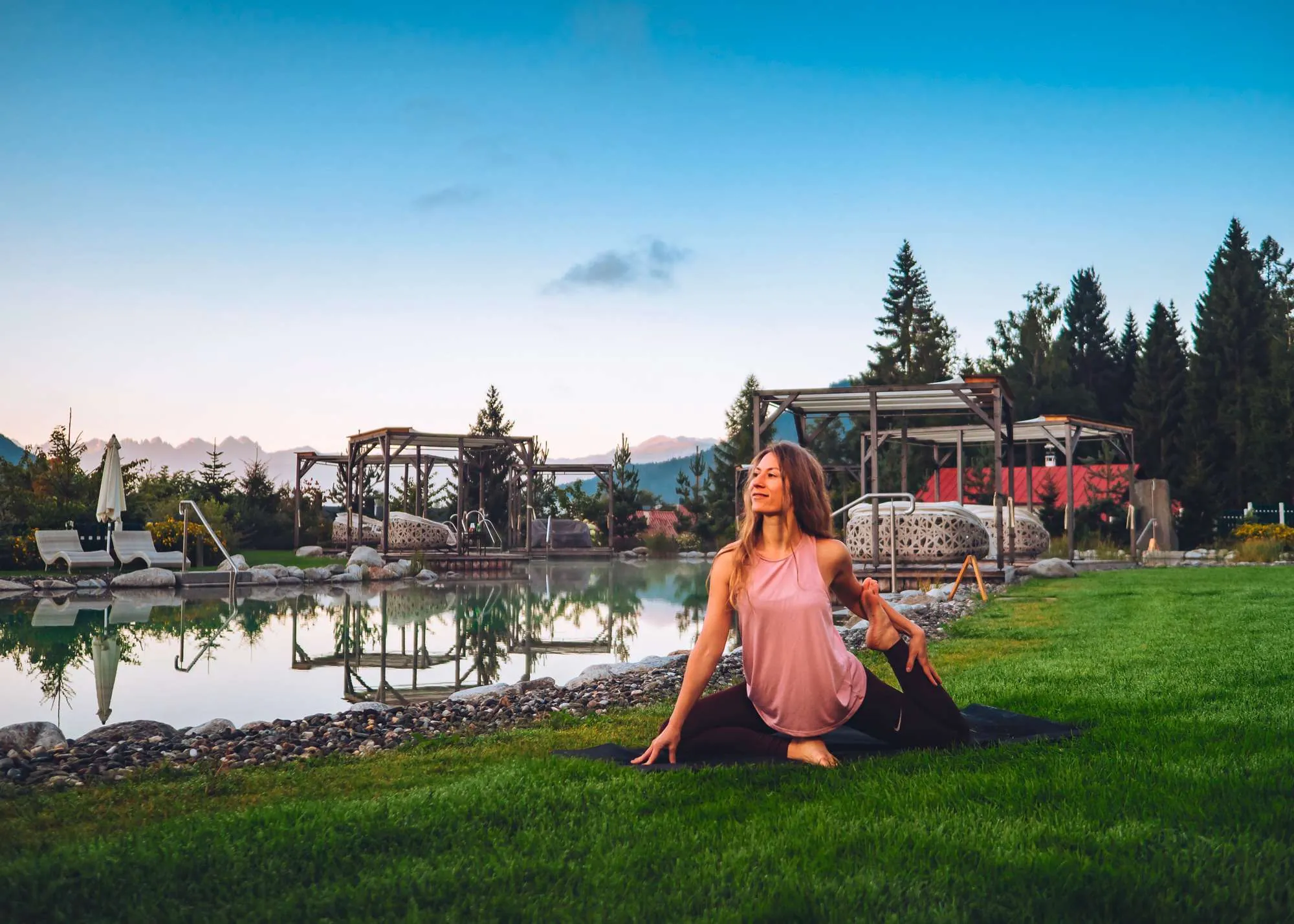 Frau macht yoga drau&szlig;en auf dem Rasen bei D&auml;mmerung