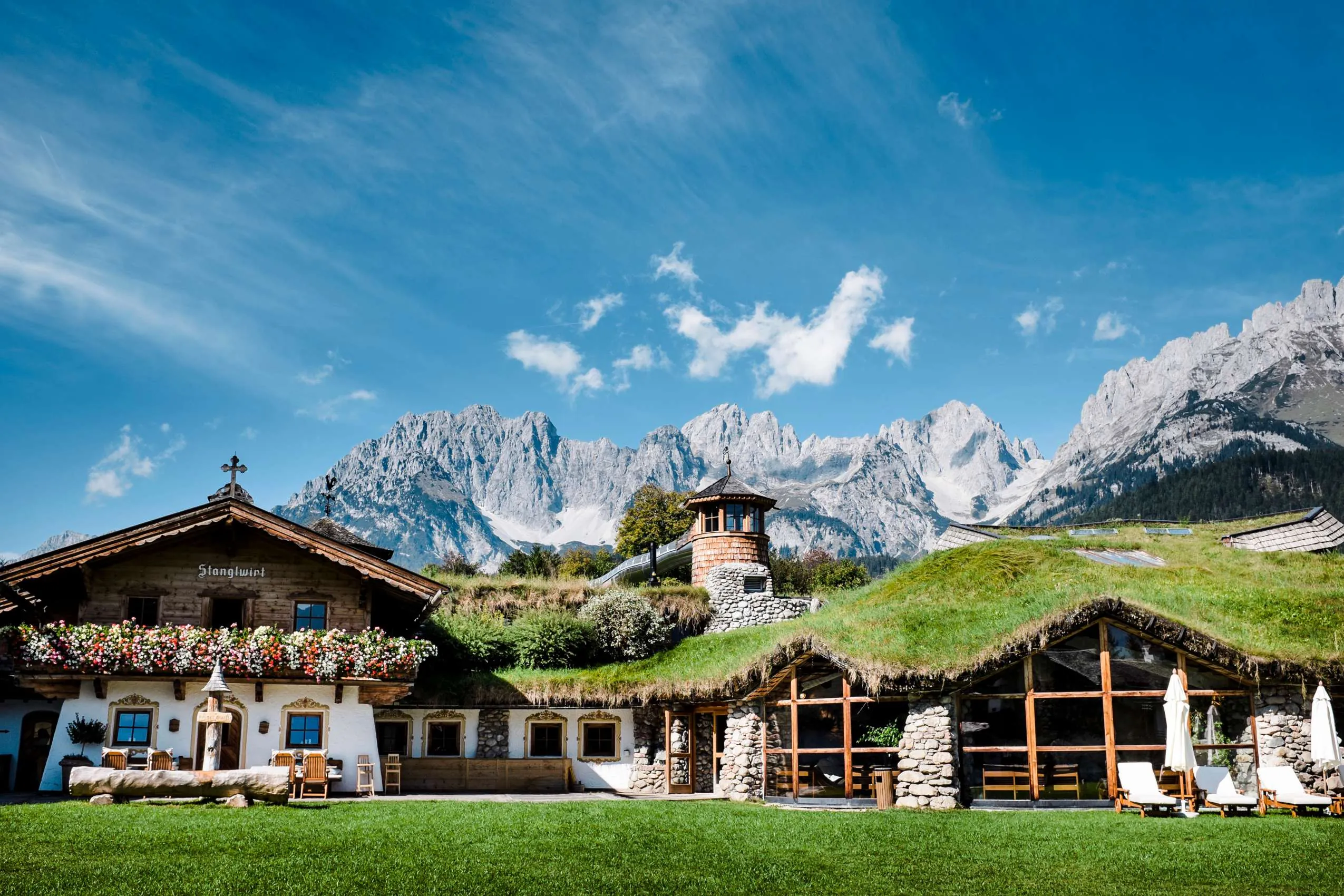 Teilgeb&auml;ude des Bio- und Wellnessresort Stanglwirt mit Bergkette im Hintergrund