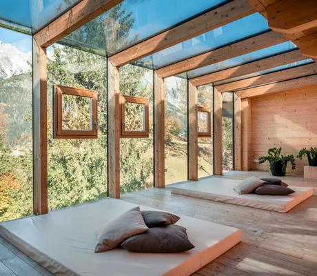 Raum im Rooftophotel Forsthofalm in Österreich mit großer Fensterfront und zwei Matratzen auf denen Kissen liegen