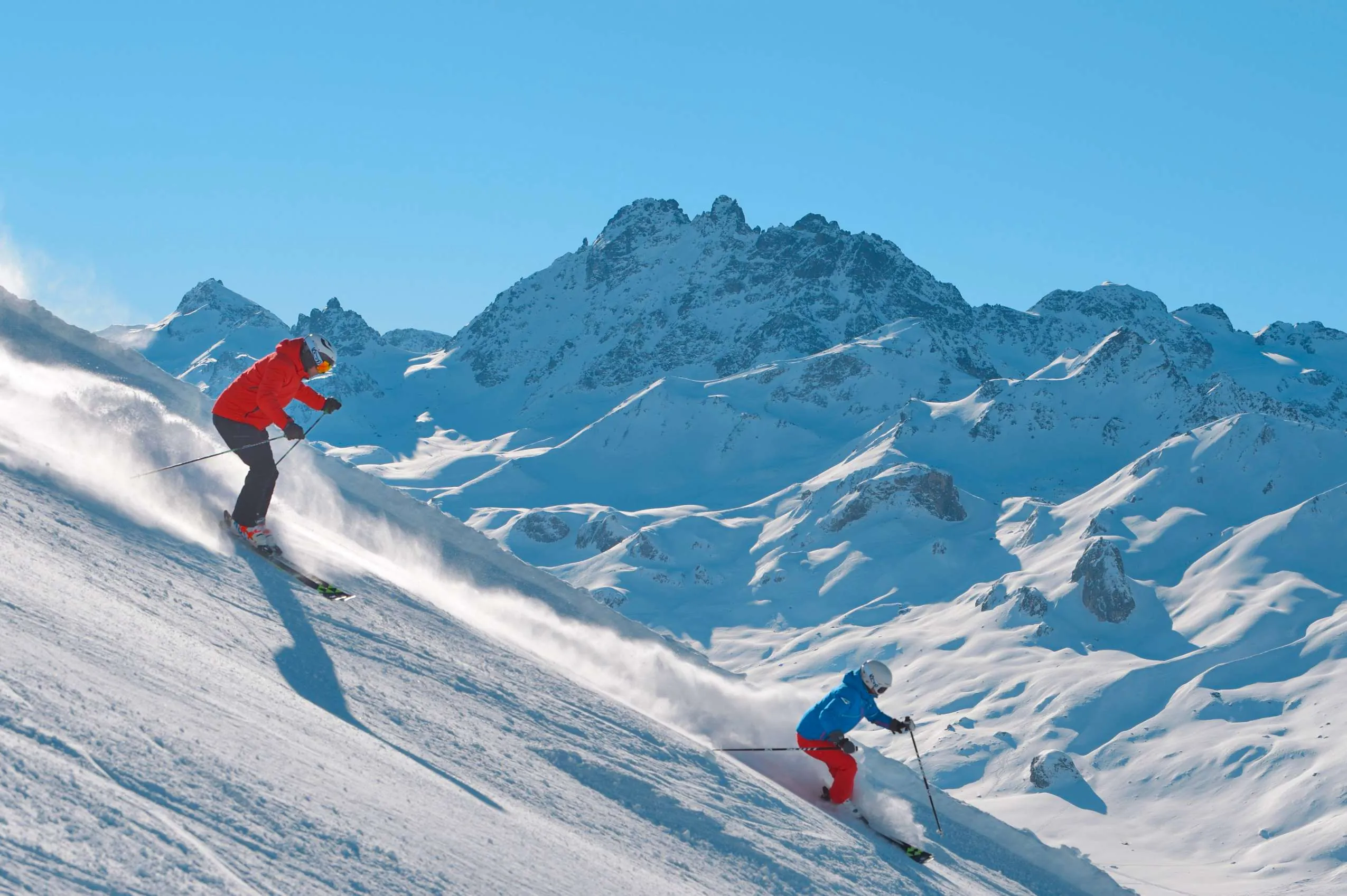 Zwei Skifahrer fahren bei strahlendem Sonnenschein im Skigebiet Jaenner Ski
