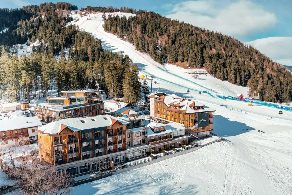 Blick auf das verschneite Excelsior Sporthotel in S&uuml;dtirol mit Skipiste im Hintergrund