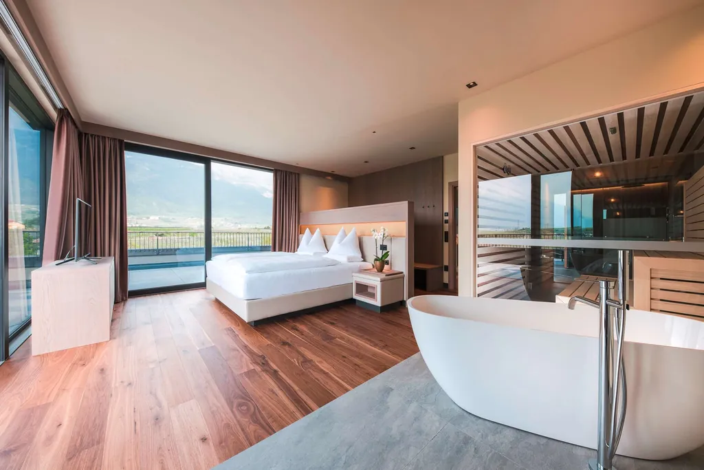 Blick in ein Zimmer des Weinegg Wellviva Resort mit einer freistehenden Badewanne im Vordergrund