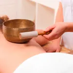 Frau liegt auf einer Liege und genießt eine Klangschalenmassage