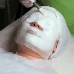Einer Frau wird eine Modelage aufgetragen und mit einem Pinsel Gips auf das Gesicht gestrichen