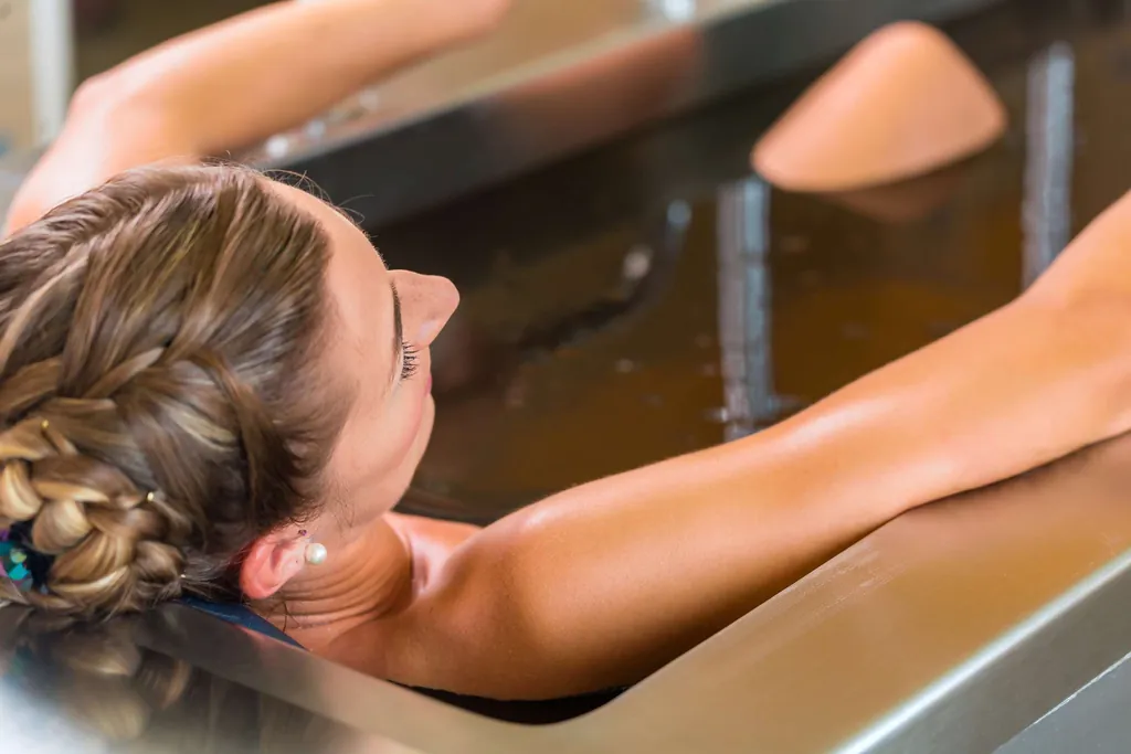 Frau liegt entspannt in einem Moorbad