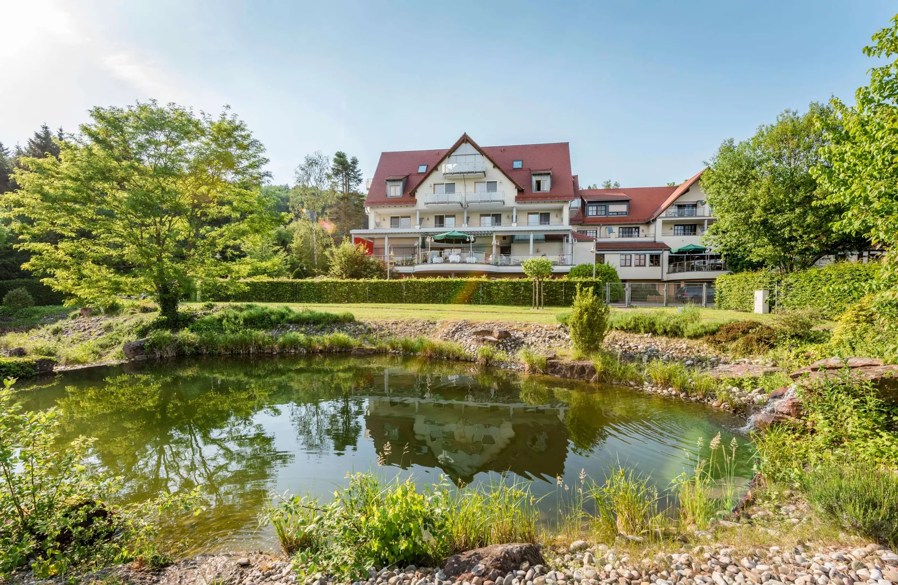 Blick über Teich auf das Landhotel Heimathenhof