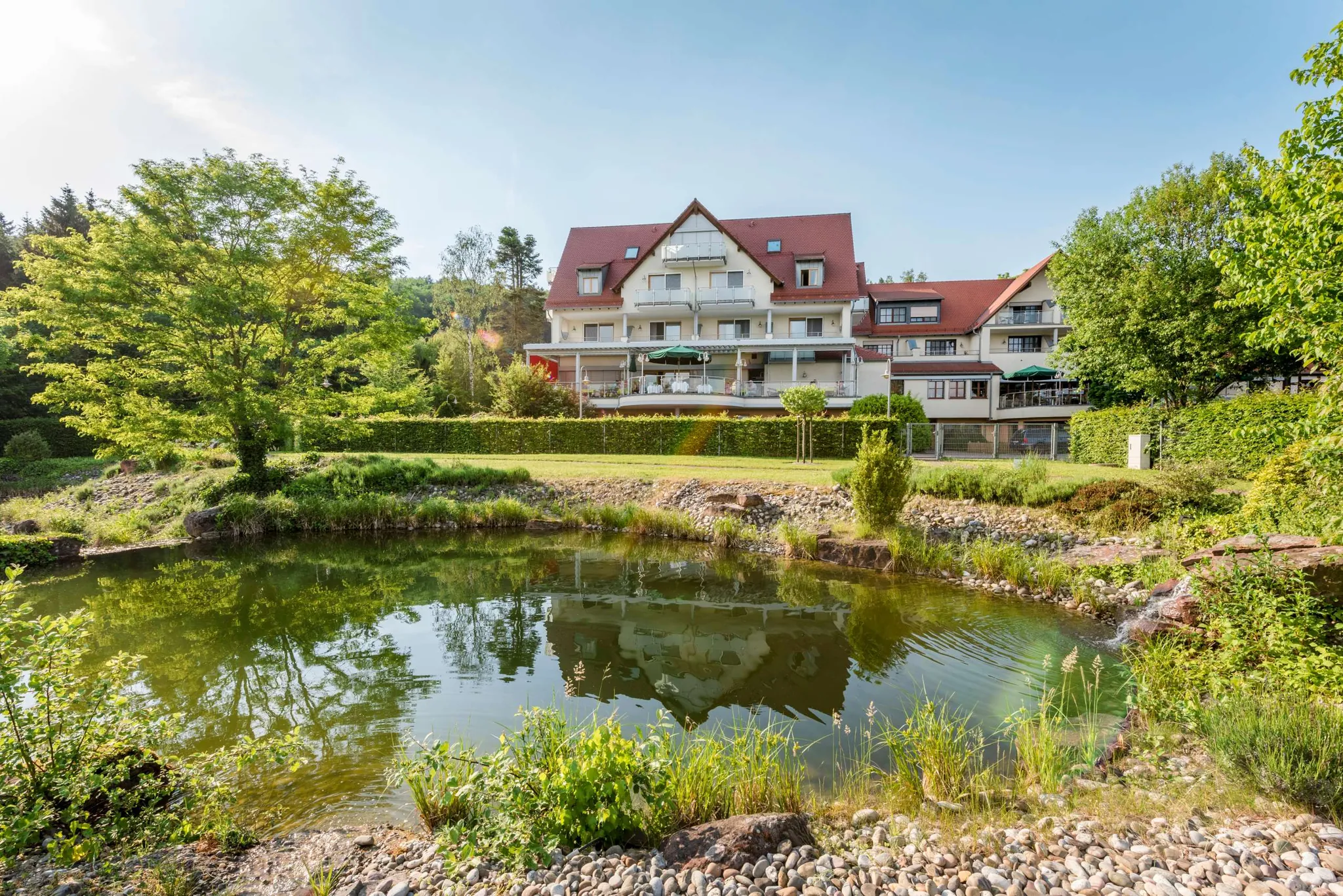 Blick über Teich auf das Landhotel Heimathenhof