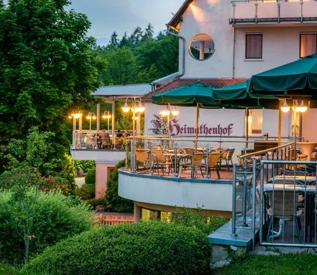 Terrassen mit grünen Sonnenschirmen und Schriftzug des Landhotel Heimathenhof