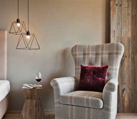 karierter Sessel mit Samtkissen neben dem Bett im Natur & Spa Hotel Lärchenhof