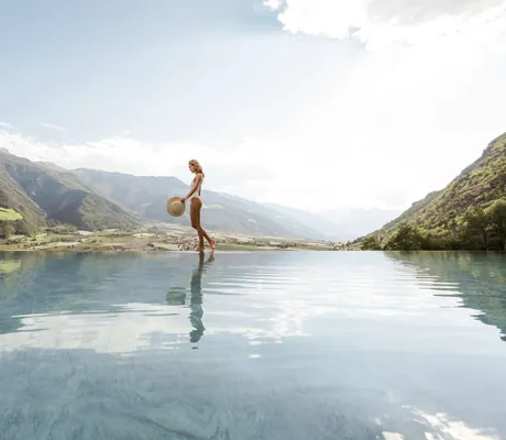 Frau in weißem Badeanzug am Infinitypool im Preidlhof