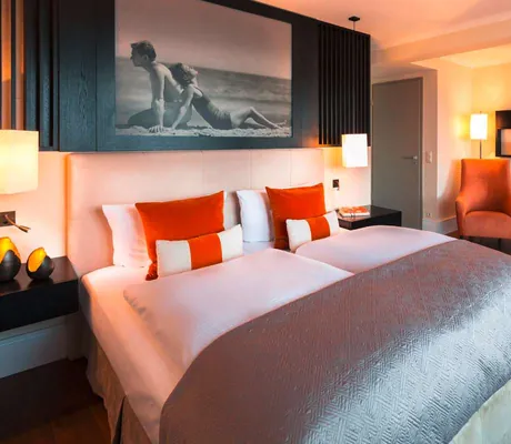 Doppelzimmer mit orangen Sesseln und Schwarz/Weiß-Fotografie über dem Bett im Strandhotel Ostseeblick