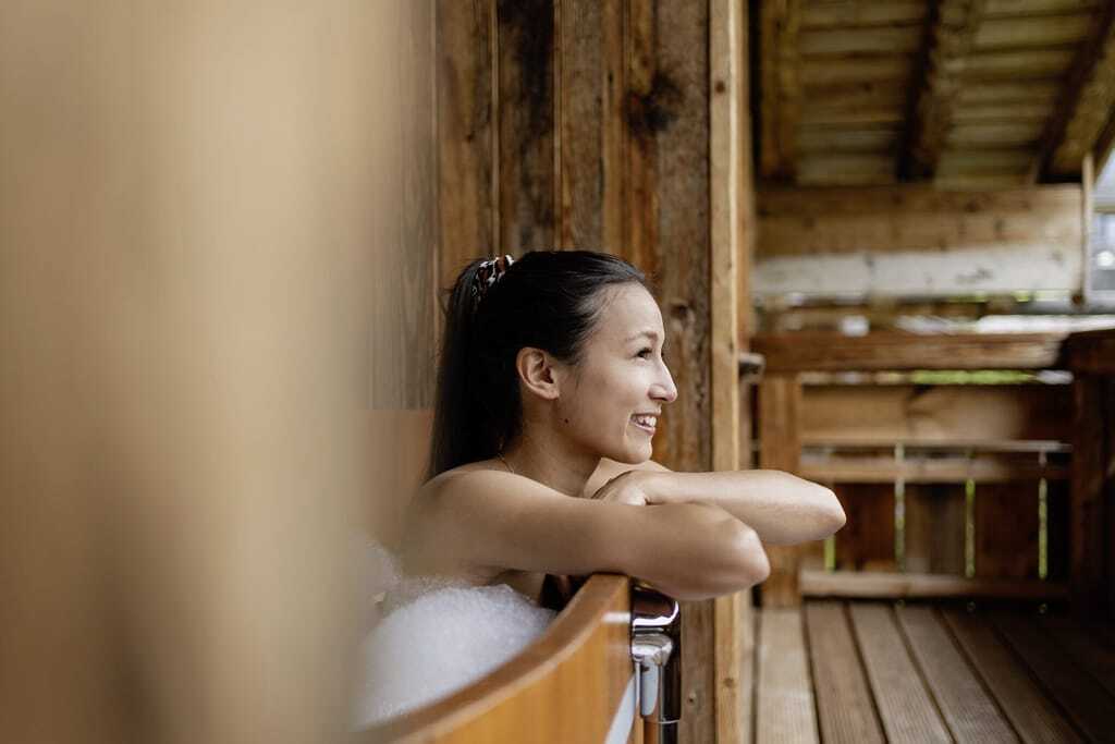 Junge Frau im Hot Tub auf dem Balkon der Alpin Chalets Oberjoch