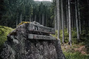 Auf einem Stein wurde ein Holzschild montiert, auf dem "Nationalpark Hohentauern" steht
