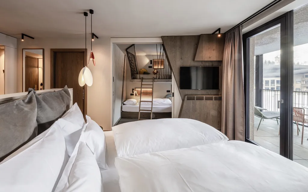 Modern gestaltetes Familienzimmer im Falkensteiner Family Resort Lido mit Doppelbett und Schlafkojen