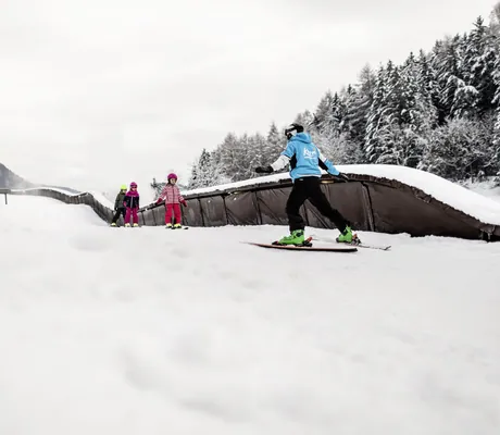 Kinder beim Skifahren auf dem Dach des Falkensteiner Family Resort Lido