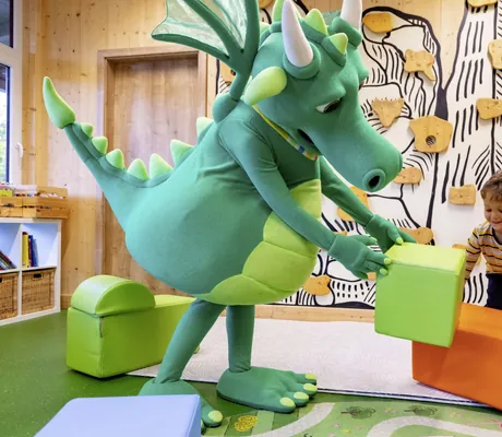 Drachen-Maskottchen des Familotel Elldus Resort spielt zusammen mit Junge im Spielzimmer