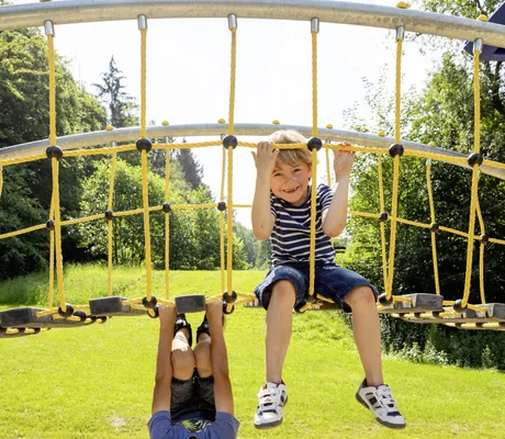 Zwei Jungs klettern auf dem Klettergeruest im Familotel Ottonenhof