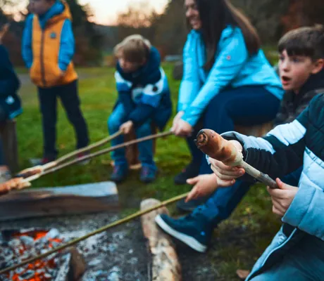 Kinder sitzen mit Stockbrot ums Lagerfeuer, Freizeitprogramm im Sporthotel Grafenwald