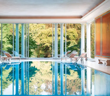 Indoorpool mit Säulen und roten Wänden in Brenners Park-Hotel