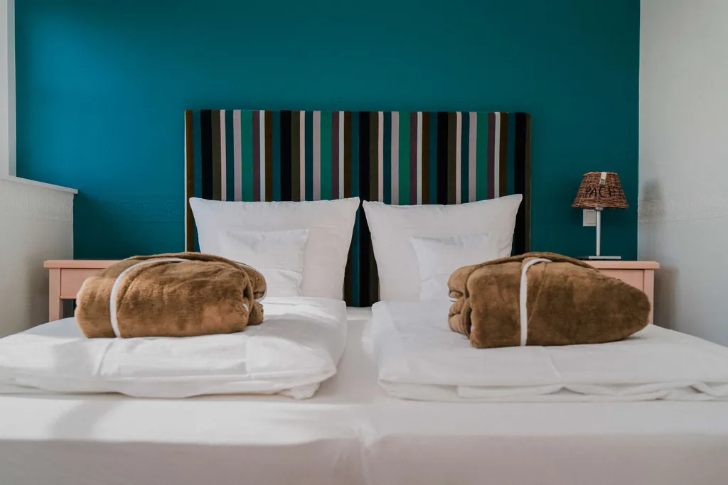 Doppelbett mit gestreiftem Bettkopf und braunen Bademänteln im Lundenbergsand