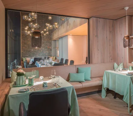 eingedeckte Tische in Grau und Mint vor großem Spiegel im Restaurant des Naturhotel Waldklause