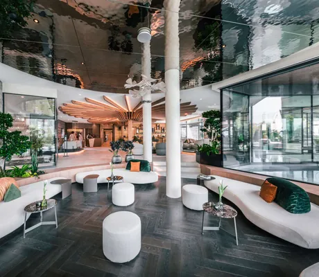 Lobby mit weißen Sitzmöbeln und verspiegelter Decke im Quellenhof See Lodge