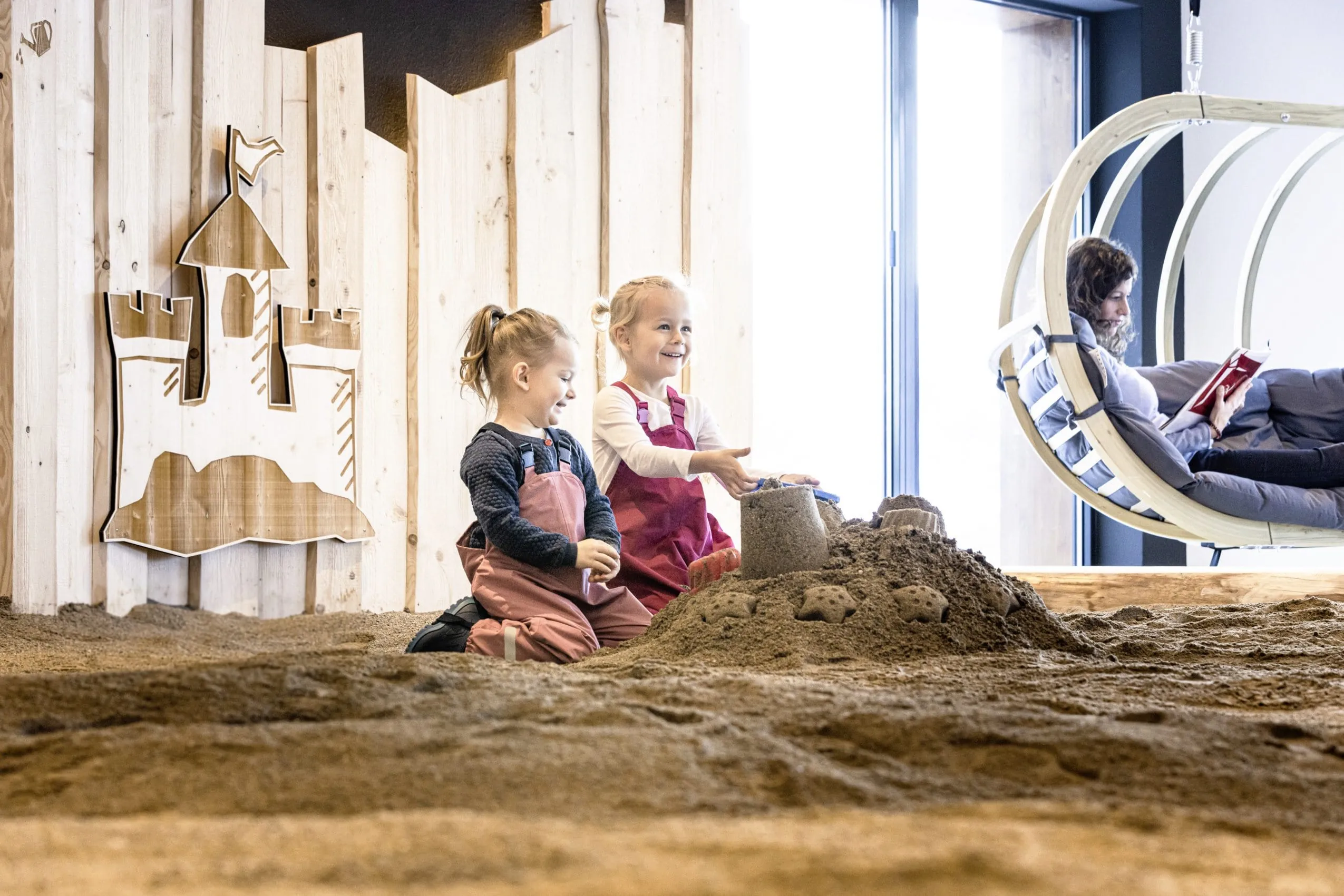 zwei M&auml;dchen in Matschhose im Indoor-Sandkasten des Allg&auml;uer Berghof
