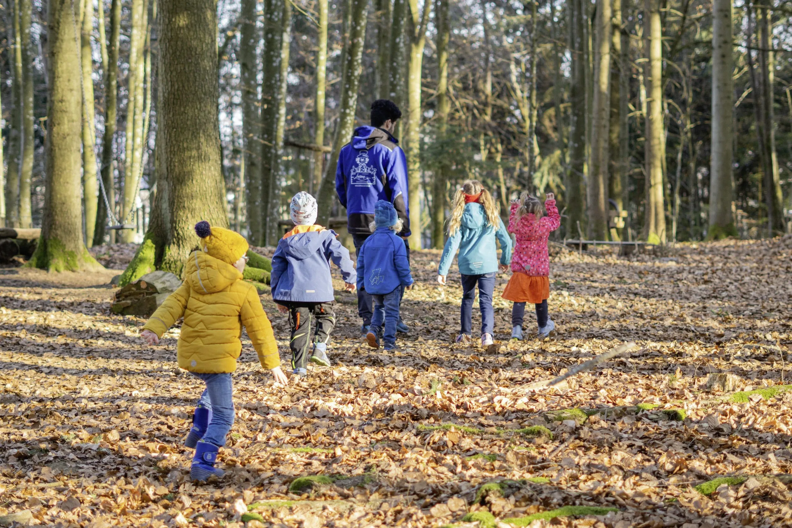 Gruppe von Kindern mit Betreuer beim Wald-Erlebnisprogramm des Kinderhotels