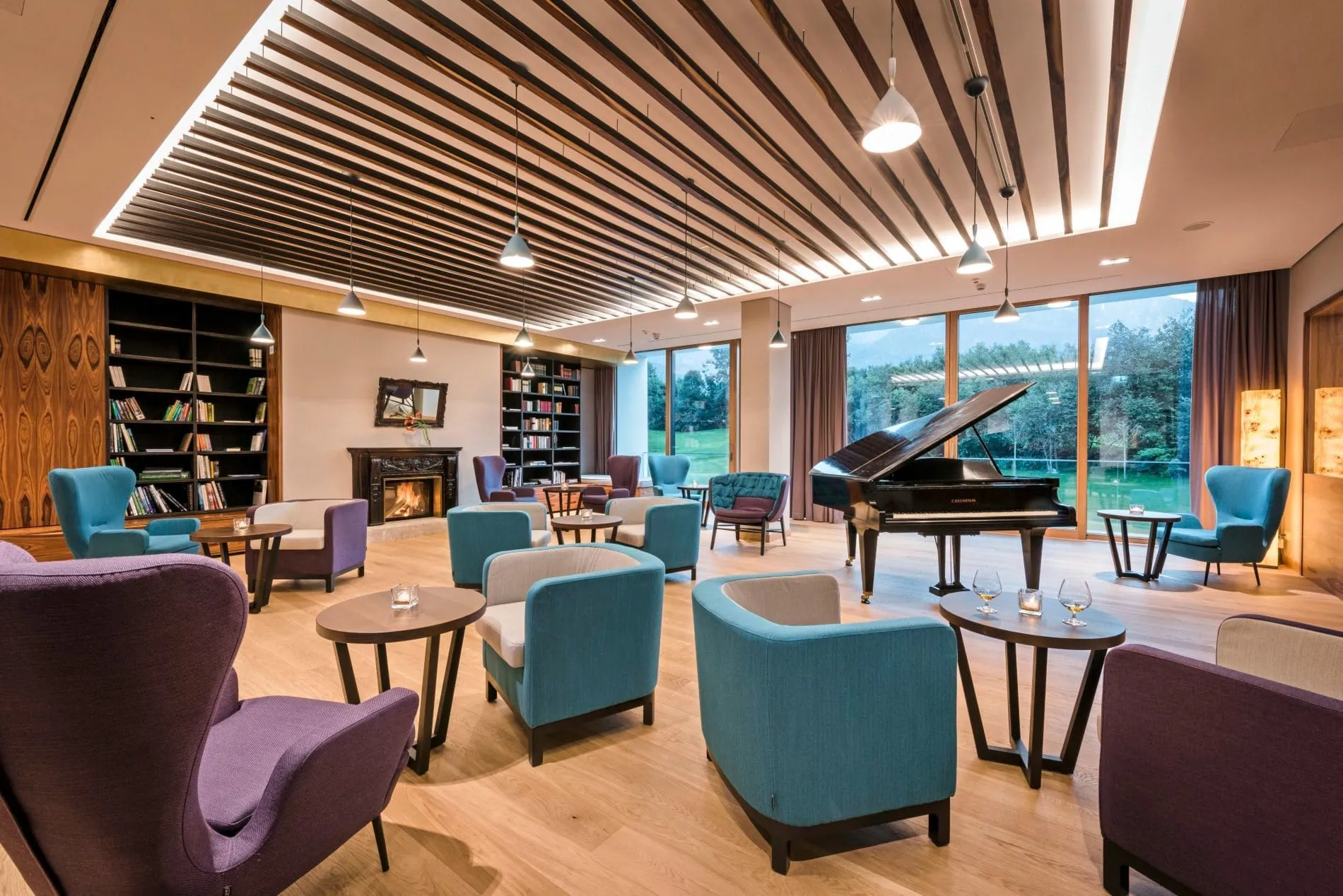 Lounge mit farbigen Sesseln, Piano und B&uuml;cherregalen im Klosterhof &ndash; Alpine Hideaway & Spa