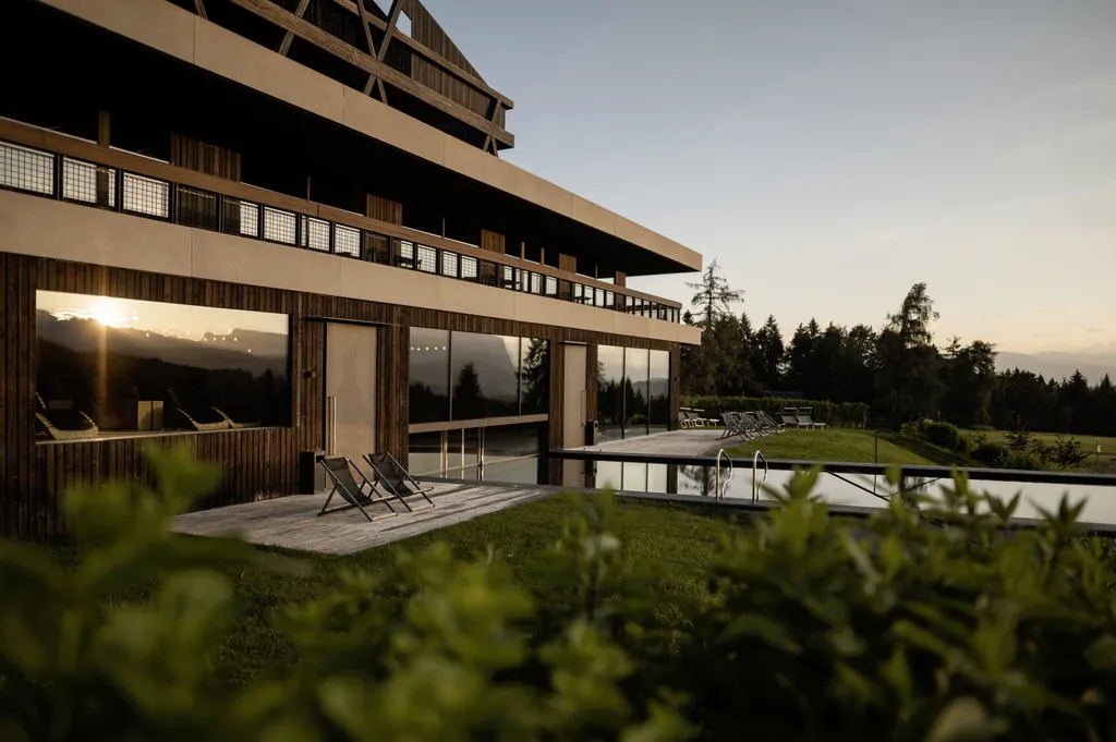 Die Fassade des Naturhotel Pfösl glänzt rötlich im Sonnenuntergang