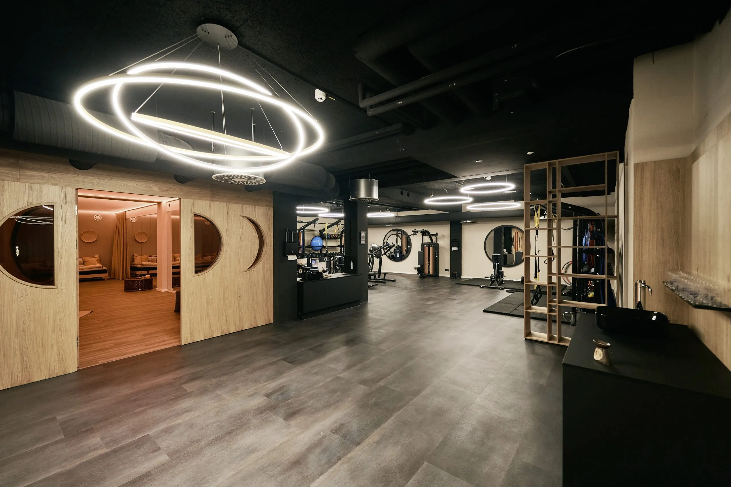 moderner Fitnessbereich mit gro&szlig;er Dignerleuchte im Thermenhotel Holzapfel