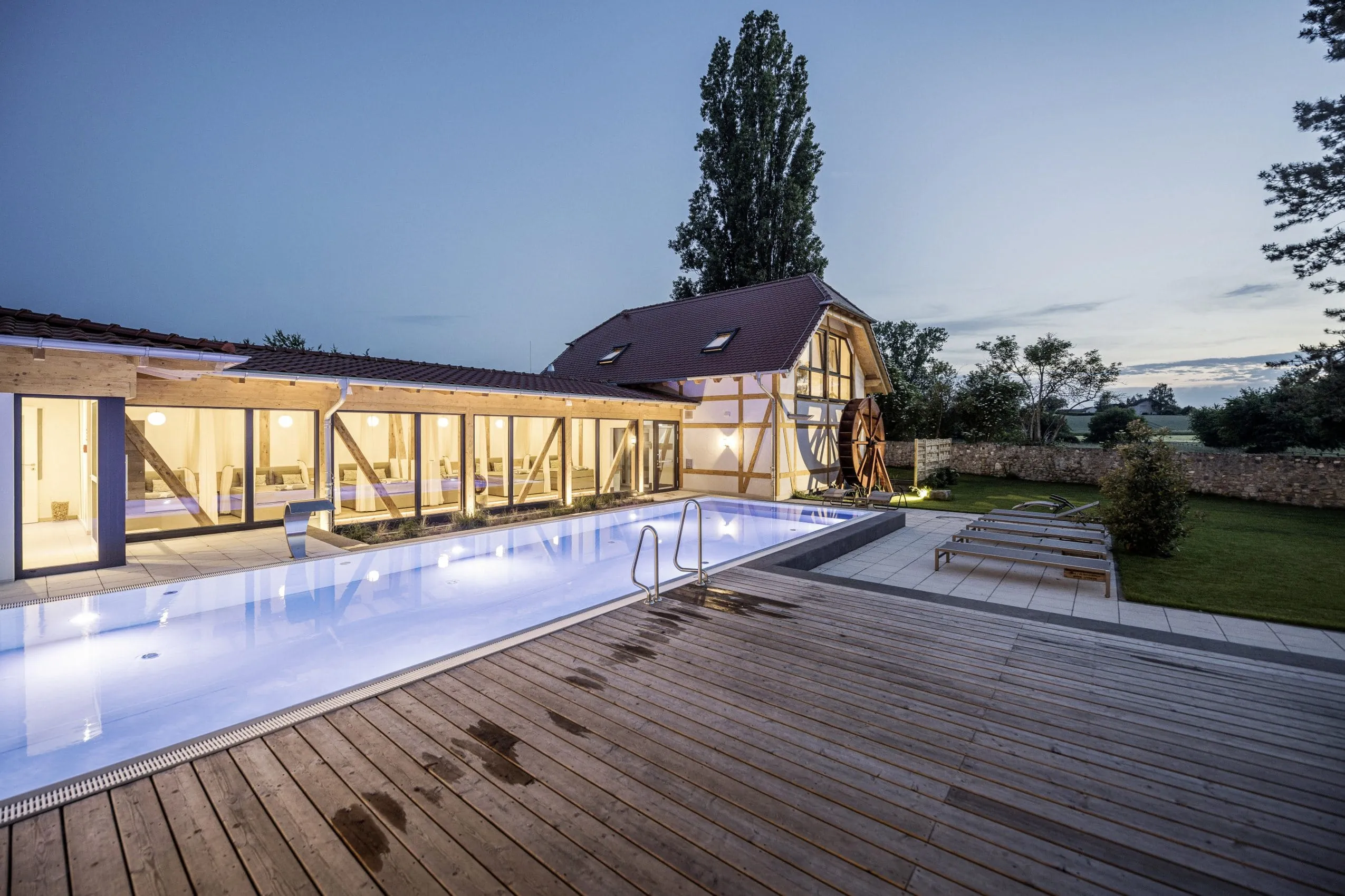Blick auf den Outdoorpool des Wellnesshotels Jordan&rsquo;s Unterm&uuml;hle in der D&auml;mmerung