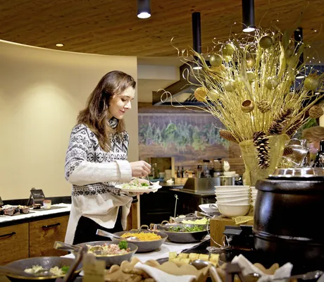 Frau im Norwegerpulli bedient sich am Frühstücksbuffet im Wellnesshotel Fontis luxury spa lodge