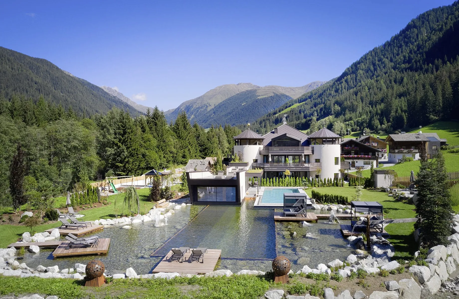Gesamtansicht des Wellnesshotels Fontis luxury spa lodge mit Naturbadeteich und Outdoorpool