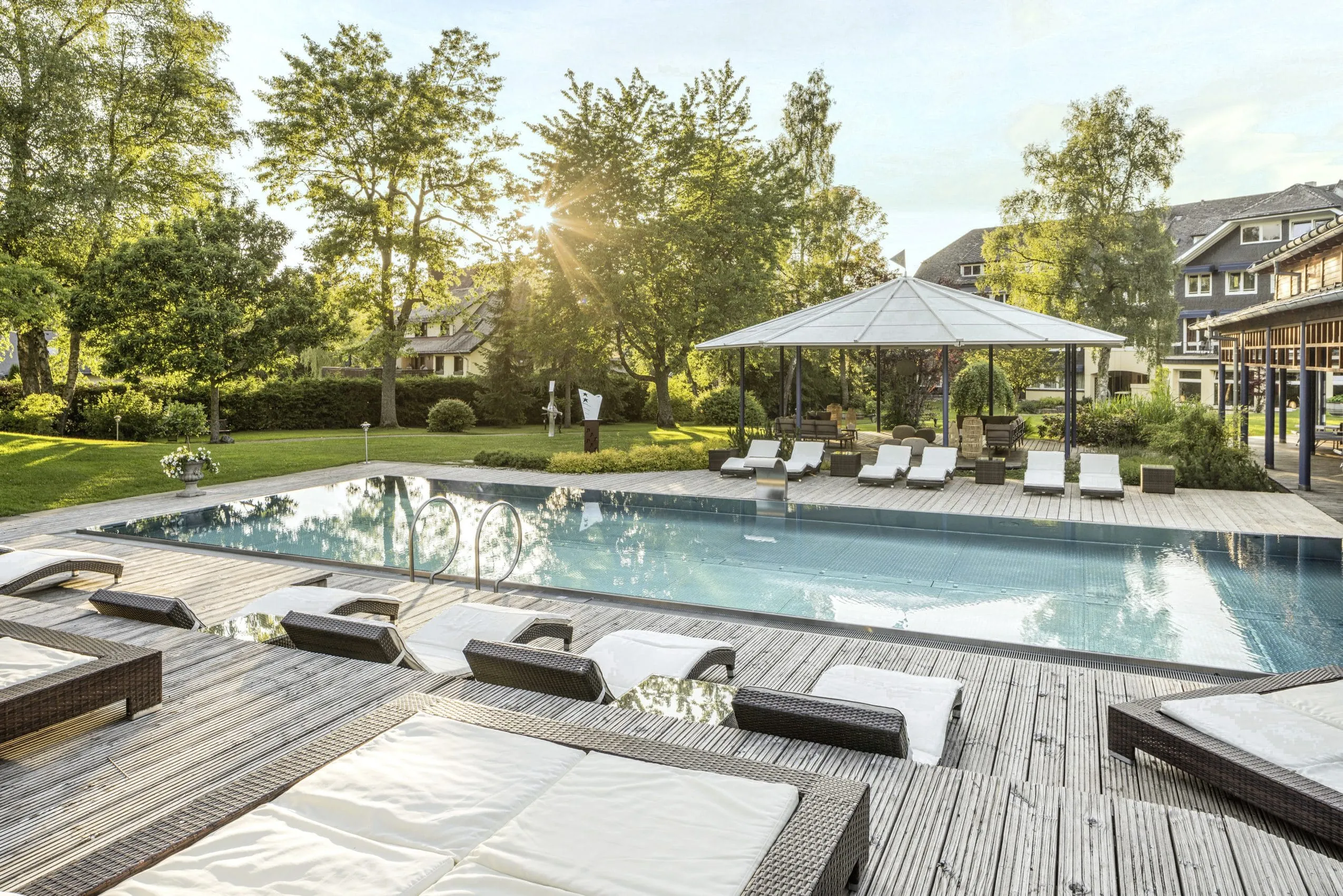 Outdoorpool mit Liegen und Blick auf den Wellnesspavillon im Parkhotel Adler