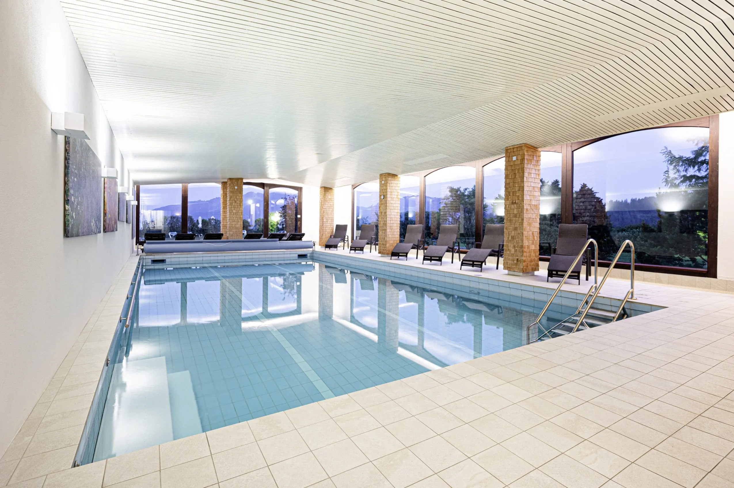 Innenpool im Mittelburg Wellnesshotel mit gro&szlig;en Panoramafenstern und Blick auf die umgebende Natur