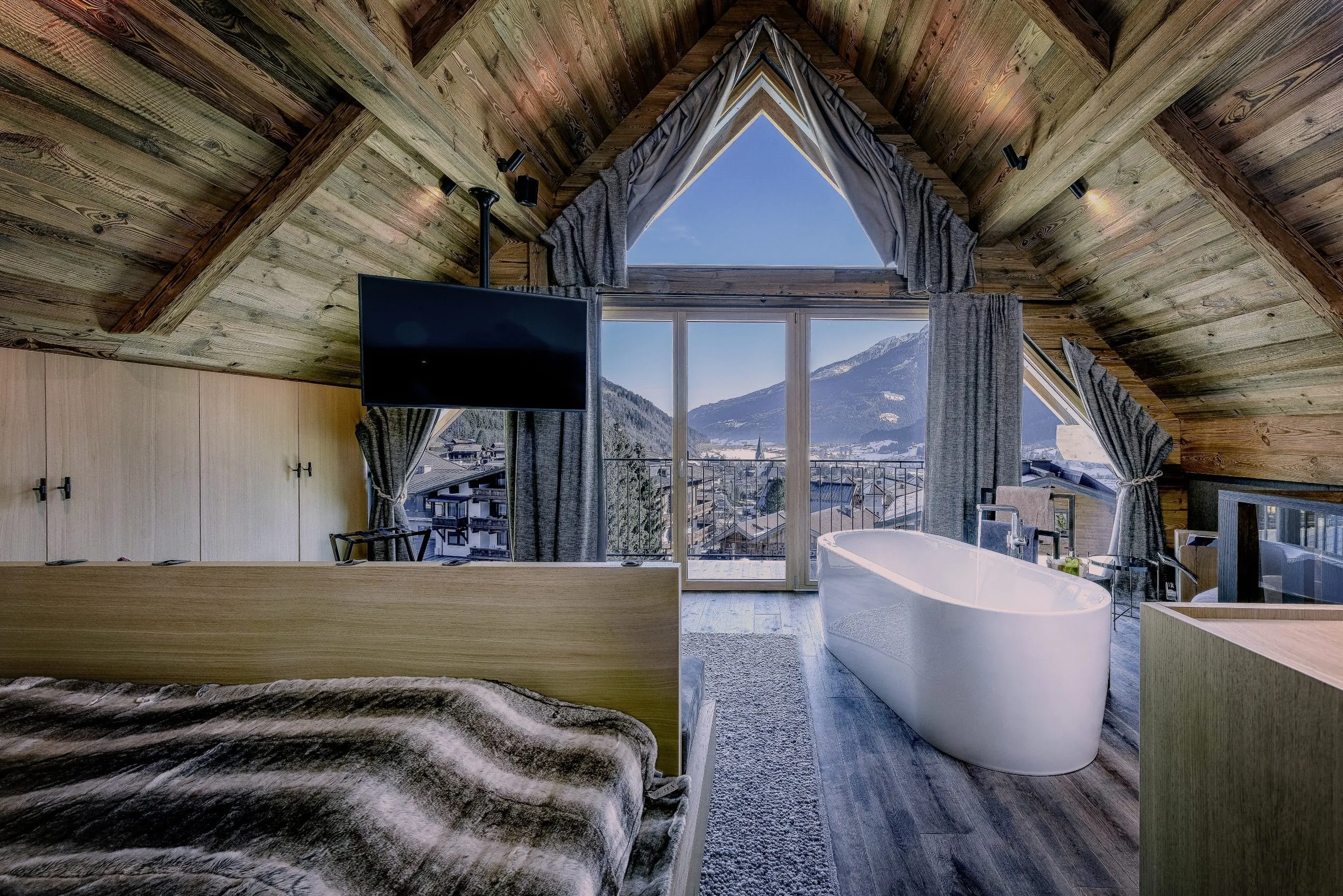 Schlafzimmer mit freistehender Badewanne und Blick auf die Berge im Baumhaus des Hotel Gassner