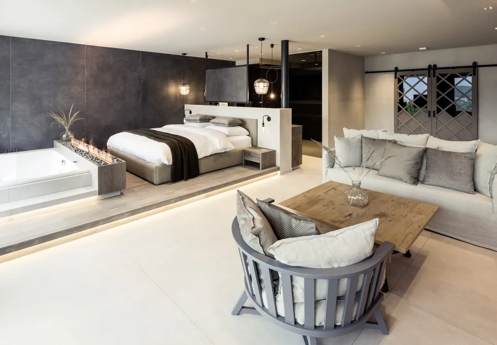 Zimmer mit Doppelbett, Sofa und freistehender Badewanne im PURMONTES Private Luxury Chalet in Südtirol