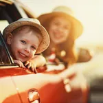 Kleiner Junge mit Sommerhut schaut aus dem Auto