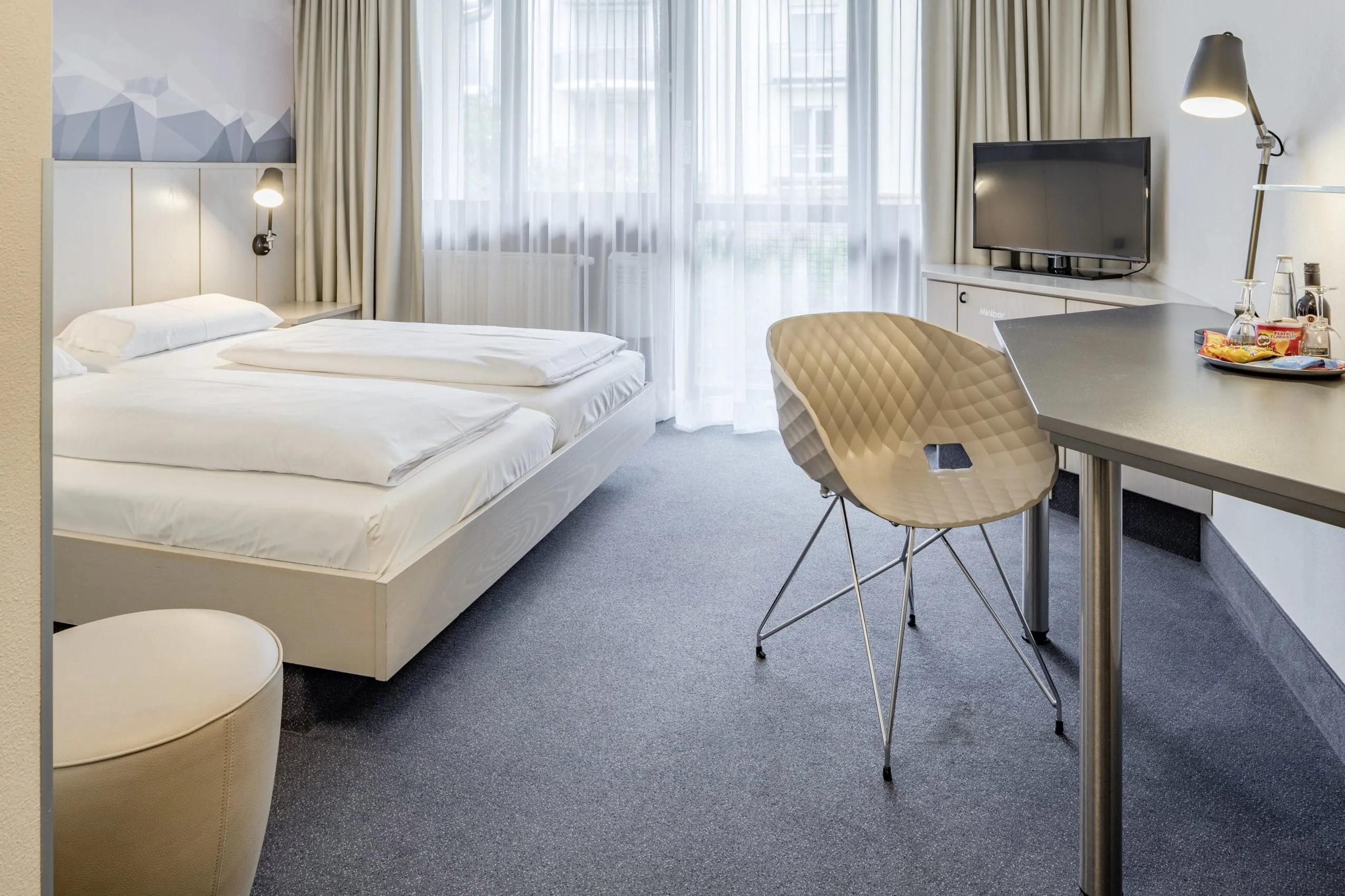 Helles Doppelzimmer mit Fernseher und Tisch im Tagungshotel in Bayern