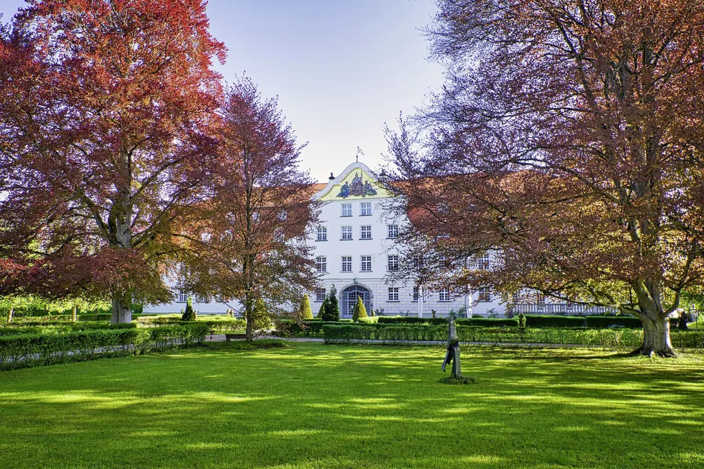 Parkanlage mit bunt gef&auml;rbten B&auml;umen und Schloss Lautrach im Hintergund