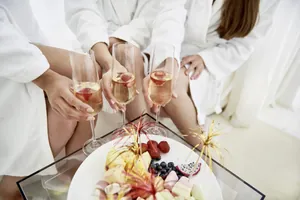 Drei junge Frauen im Bademantel stoßen im Wellnessbereich des Hotel Franks mit Sekt an