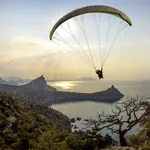 Gleitschirmflieger in der Luft mit Meer im Hintergrund