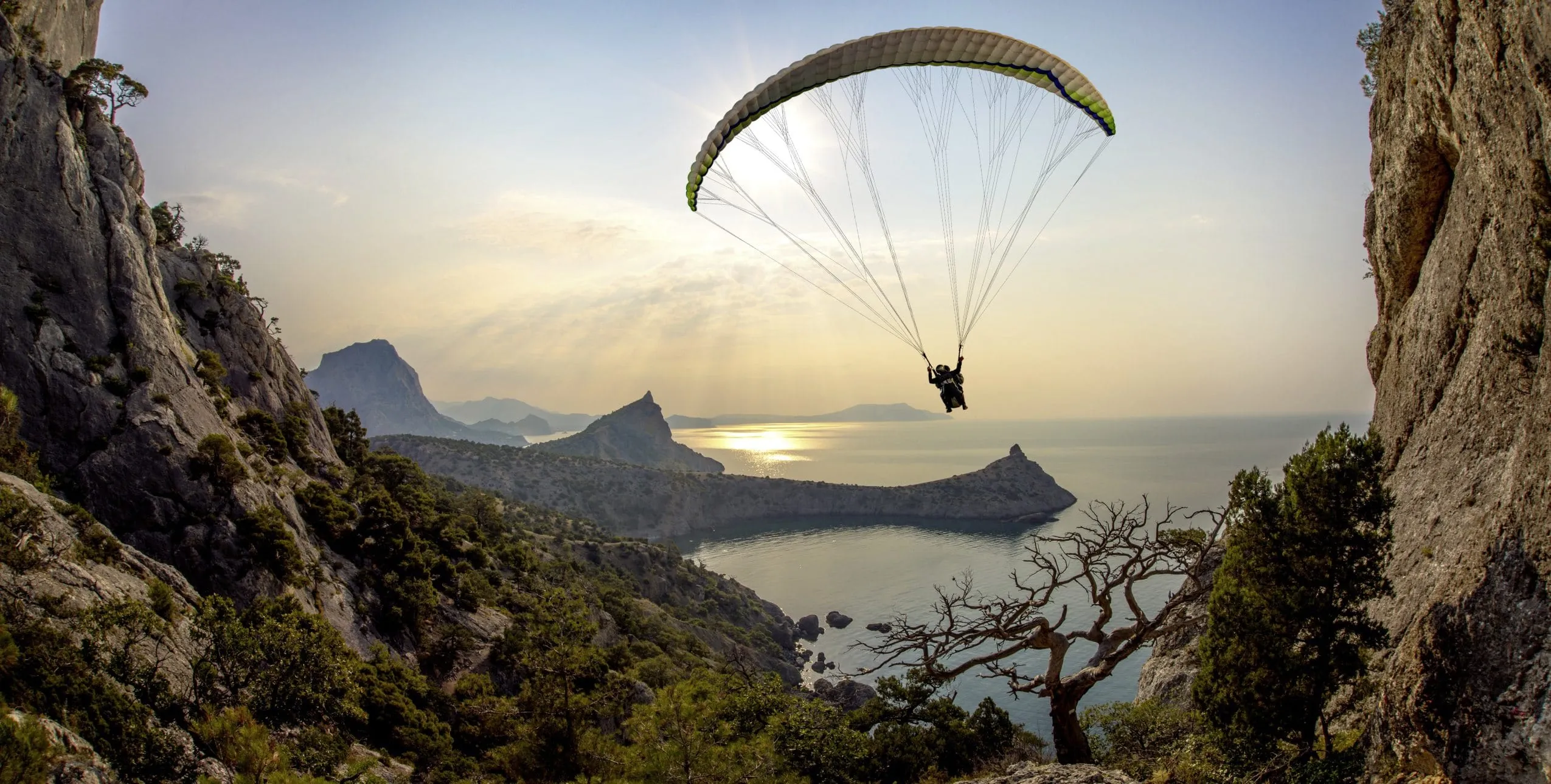 Gleitschirmflieger in der Luft mit Meer im Hintergrund