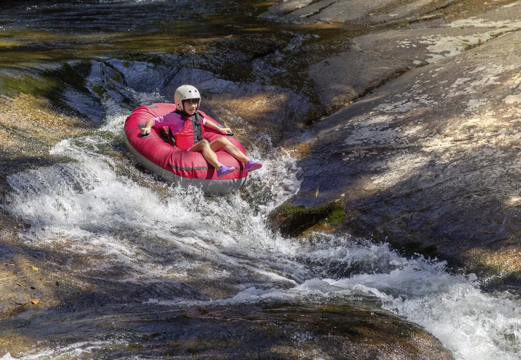 Junges Kind sitzt auf aufgeblasenem Gummiring und treibt die Flußströmung beim Wild River Tubing hinab