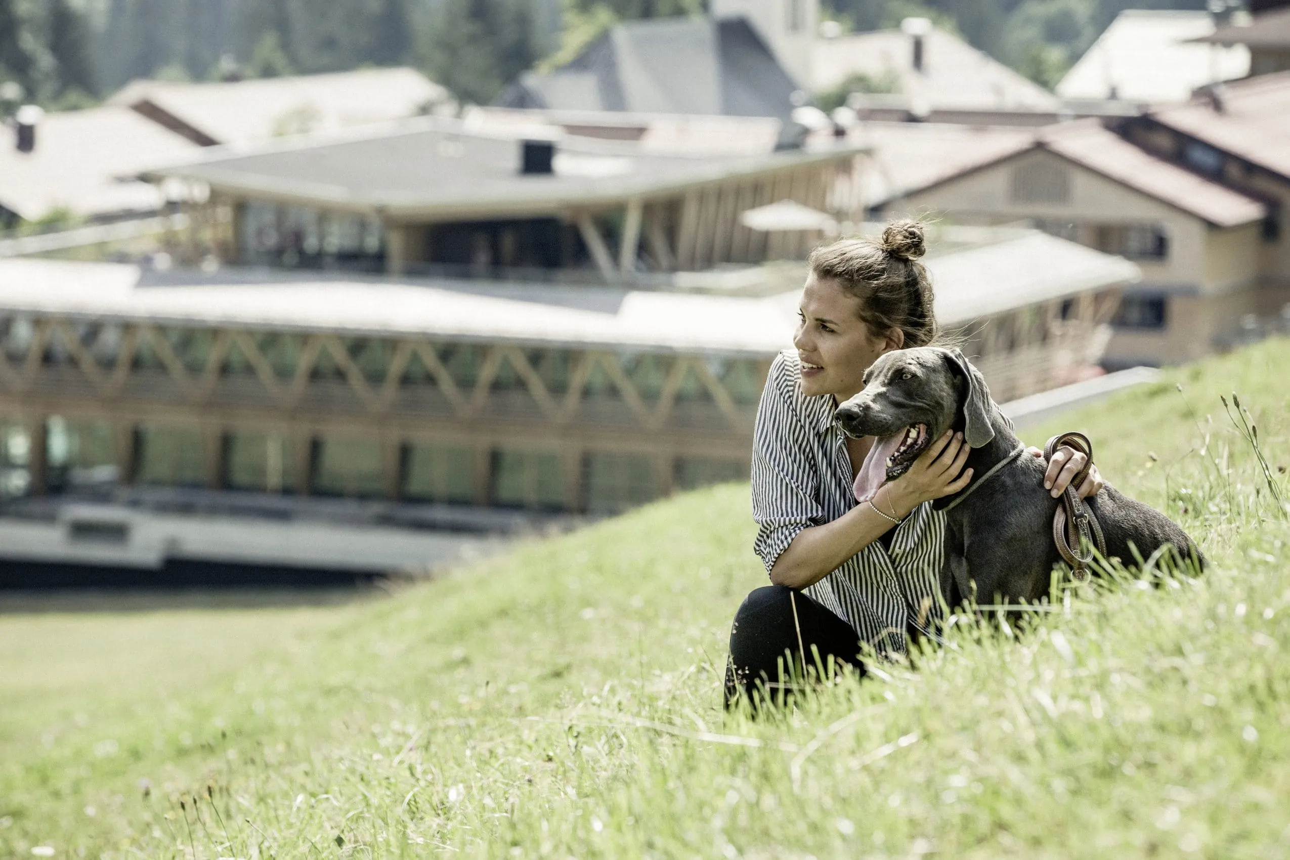 Frau mit Hund auf Wiese vor dem HUBERTUS Mountain Refugio Allg&auml;u